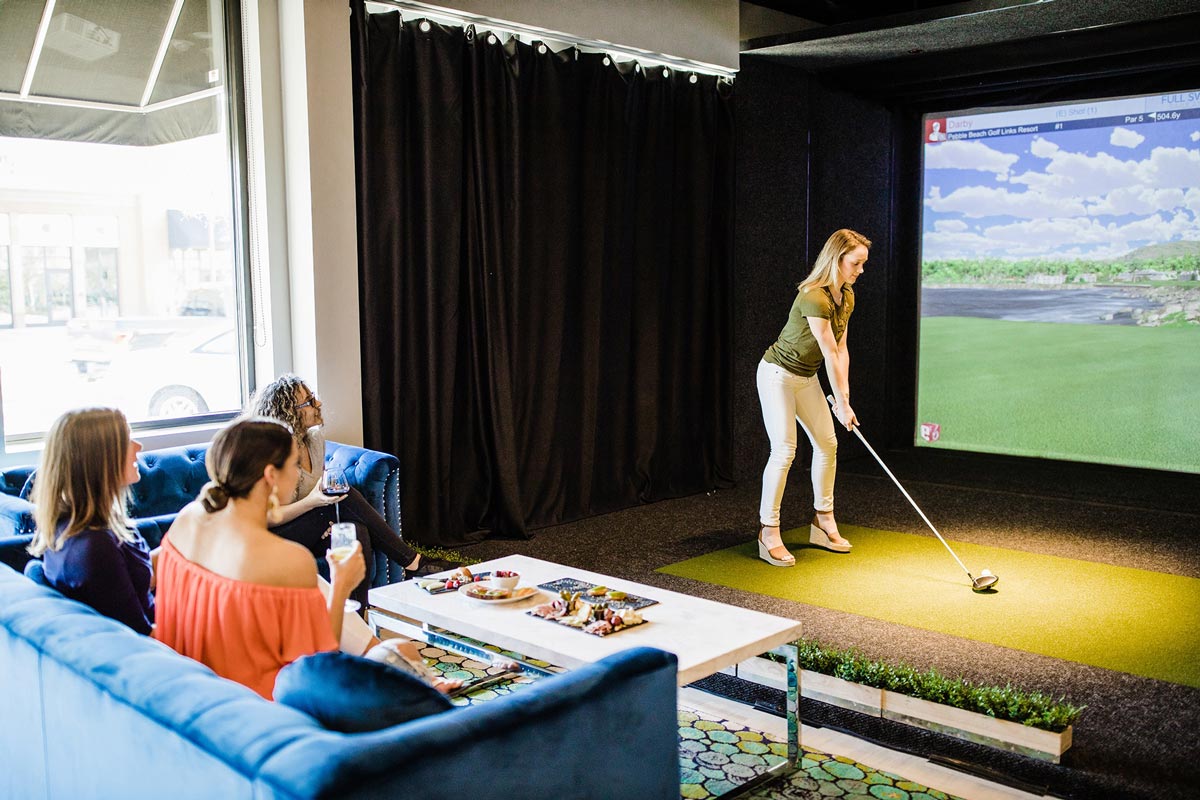 Friends playing a Full Swing golf simulator at Golfer's Den