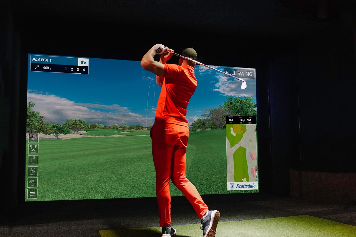 Golfer working on his swing in a simulator bay