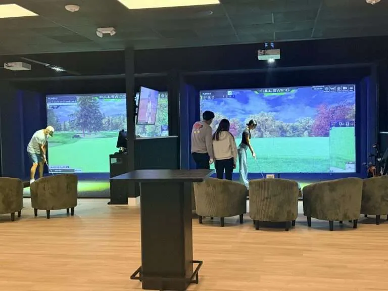 Guests playing on two Full Swing simulator bays at Golfer's Den